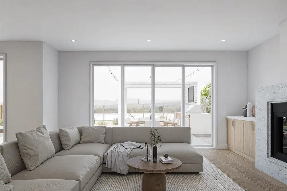 Modern living room with L-shaped beige sofa, round wooden coffee table, and wall-to-wall glass doors